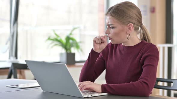 Young Woman Using Laptop Coughing in Office alt