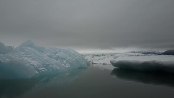 Aerial quiet ocean with icebergs on a cloudy day