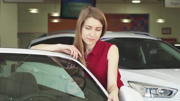 Beautiful Young Woman Posing with a New Auto at the Dealership alt