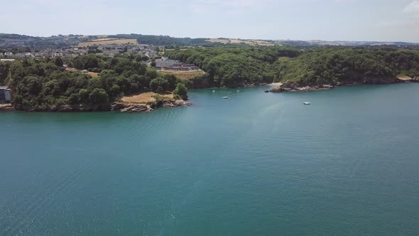 Flying towards Brixham beach in England. Boats docked off the shore. alt