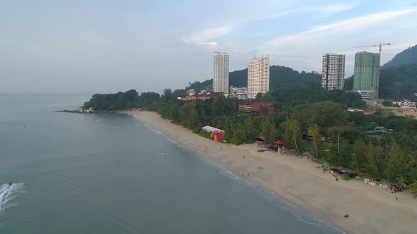 A drone shot of a parasailer behind the boat landing on the beach Batu Feringghi in  Penang, Malaysi alt