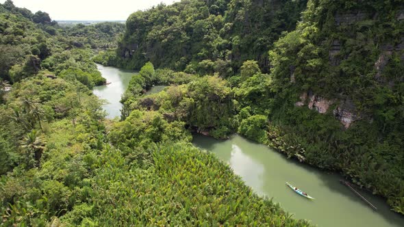 aerial drone of a local boat floating along a green river in ramang ramang south sulawesi indonesia alt