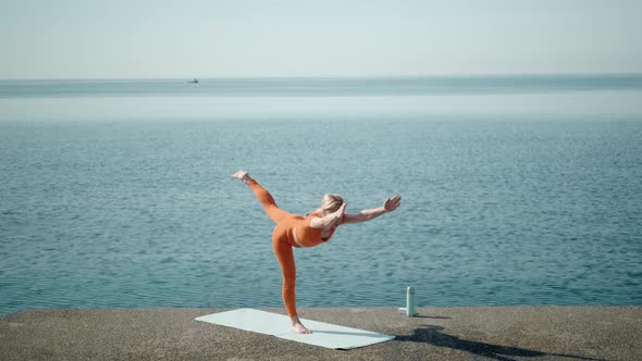 Woman Practices Yoga Near Sea and Keeps Balance