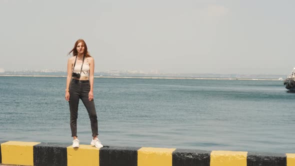Beautiful Young Woman Photographer with Red Hair Walks in the Port of Odessa alt