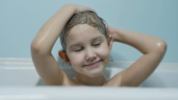 Caucasian Beautiful Teenage Girl Shampoos Her Head Hair in the Bath