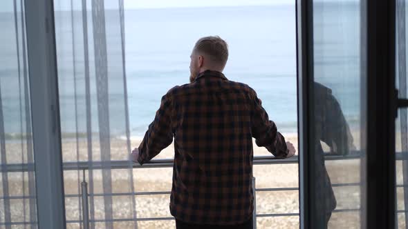 a man stands on a balcony and looks at the sea