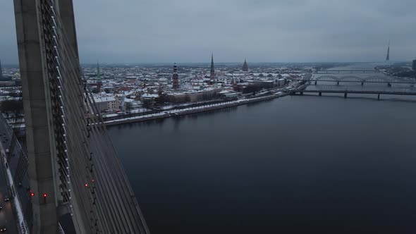 Aerial Revealing Shot of Gloomy Winter City of Riga Latvia Through Vansu Bridge alt