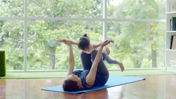 Little girl and young mother doing exercise on fitness mat alt