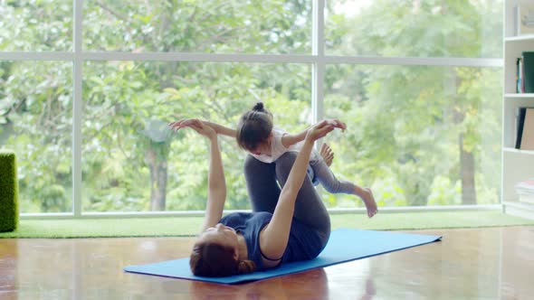 Little girl and young mother doing exercise on fitness mat