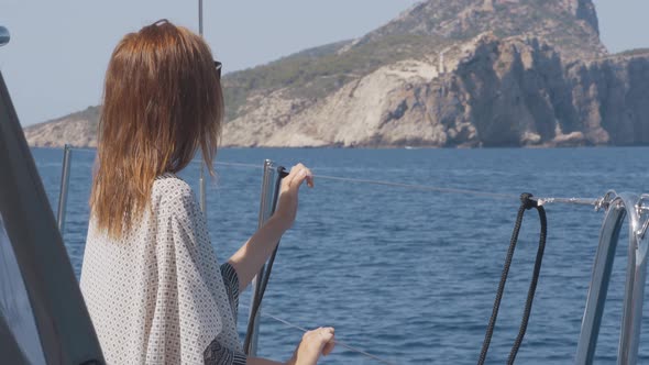 Beautiful Woman on a Yacht Enjoys the Journey on the Background of the Islands of Ibiza or Mallorca alt