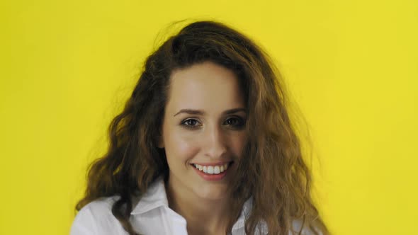 Beautiful Sexy Woman Is Looking at Camera and Flirting in Studio with Yellow Background. alt