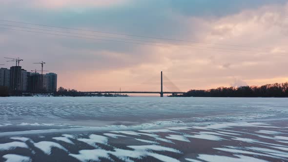 Aerial Shot of Drone Flying Above Frozen River in Urban Area alt