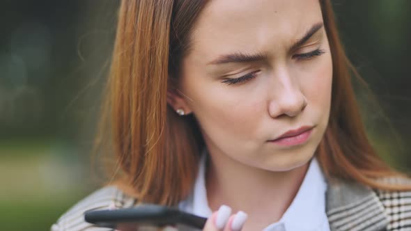 A Young Beautiful Girl Listens to an Audio Message on Her Phone alt