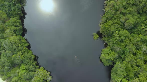 drone footage of woman swimming in black water lake alt