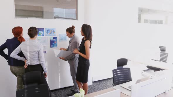 Group of executives discussing over graph 4k alt