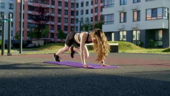 Athletic Slender Girl in Black Tight Uniform Does Plank Run on Street on Sports Ground in