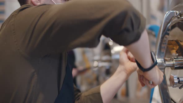 Young Male Worker or Owner in Apron and Mask Turning Valve on Large Boiler for Beer Fermentation alt