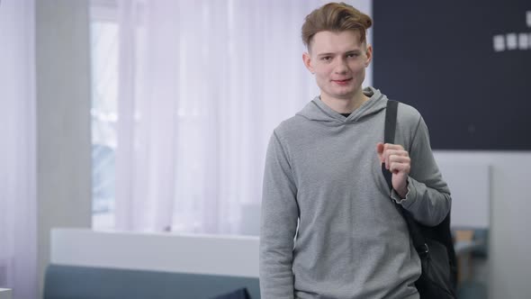 Medium Shot Portrait of Confident Intelligent Young Man with Backpack on Shoulder Posing in Student alt
