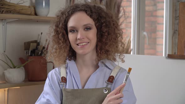 Beautiful Young Woman Artist on the Background of a White Canvas or Painting alt