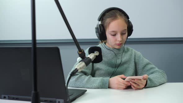 Girl in Headphones Using Smartphone While Working on Radio alt