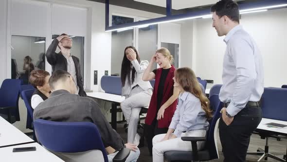 Joyful Caucasian Woman Talking to Group of Cheerful Colleagues in Office Laughing alt