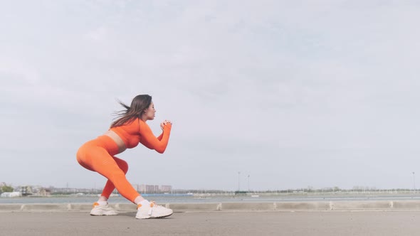 Outdoor sports. Fit girl in bright sportswear stretching her body, exercising outdoors. Girl in spor alt