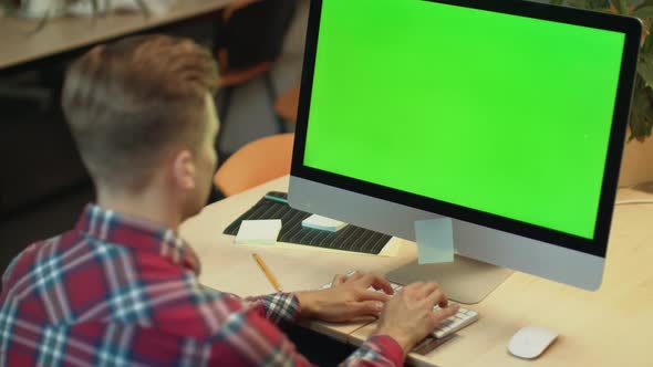 Business Man Typing on Computer with Green Screen. Young Man Working on Computer alt