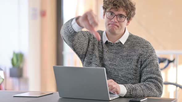Young Young Man with Laptop Showing Thumbs Down alt