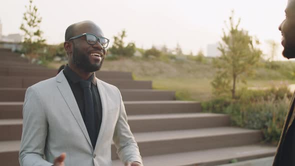 Two Black Businessmen Shaking Hands and Speaking Outdoors alt