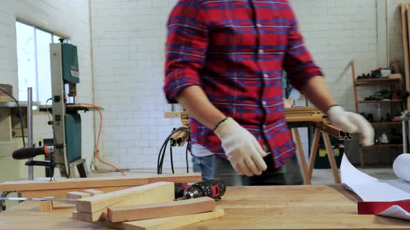 Carpenter reading drawing paper on workshop table for a build furniture project