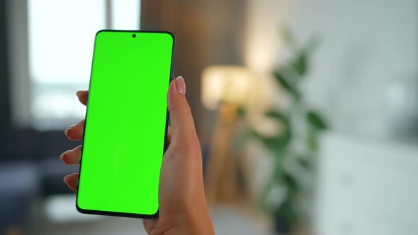 Woman at Home Using Smartphone with Green Mockup Screen in Vertical Mode alt