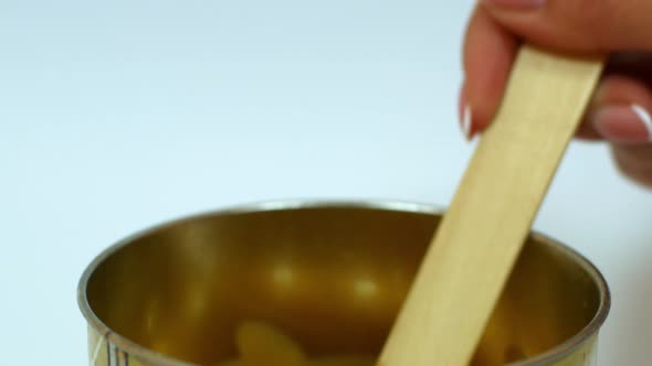 Gold depilatory wax drips from the wooden skewer before the procedure. Beauty and cosmetology alt