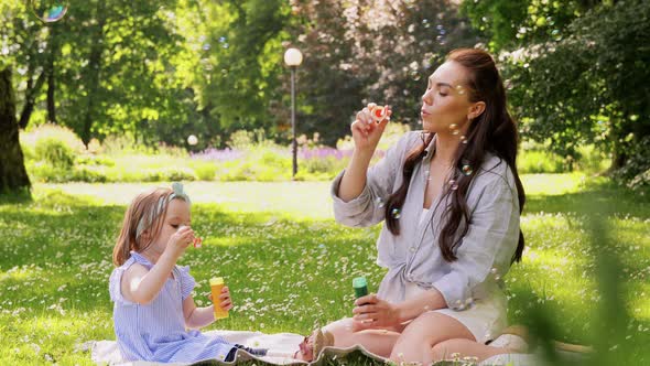 Mother with Daughter Blowing Soap Bubbles at Park