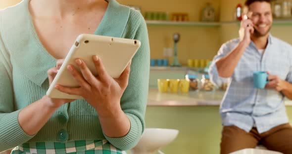 Waitress using digital tablet and man talking on mobile phone alt