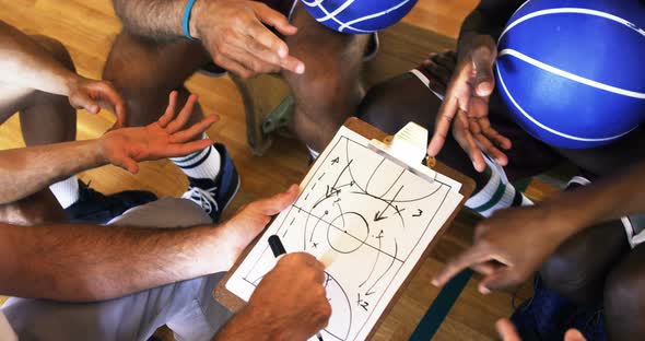 Upward view of coach assisting players on clipboard clipboard alt