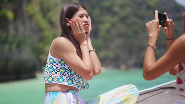 Asian woman friends using mobile phone photography together while travel on boat on summer vacation.