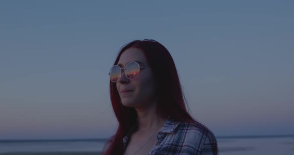 A girl with a pensive look at sunset looks into the distance alt