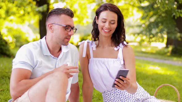 Happy Couple with Smartphone at Picnic in Park alt