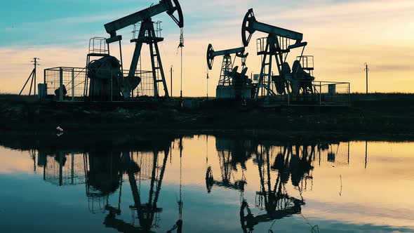 Sunset with Multiple Metal Constructions Pumping Oil. Oil Well, Crude Oil, Drilling Rig, Oil Field alt