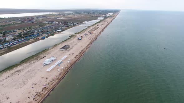 Aerial of Straight Black Sea Sand Spit with Canopies, People, Lakes, and White Sand