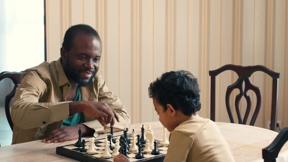 African American man explaining his son chess rules