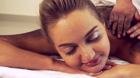 Relaxed Woman Lying on Spa Bed for Body Scrubbing Massage Using Traditional Herb alt