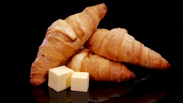 Fresh baked crusty croissants with butter. French croissants rotating on a black background. 