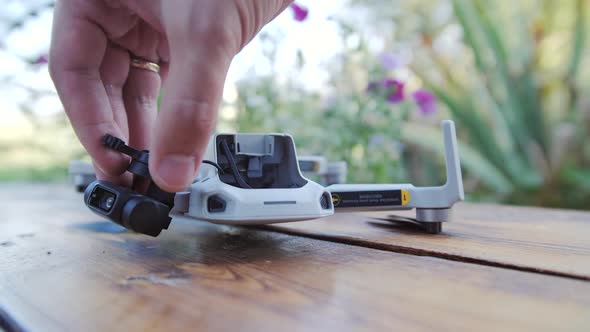 Close Up a Man's Hand Lifts Body of a Broken Drone with Wooden Floor alt