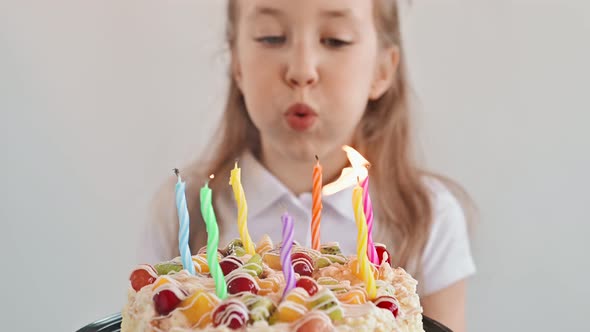 Closeup of Cute Girl Blows Out Candles on a Cake on Birthday