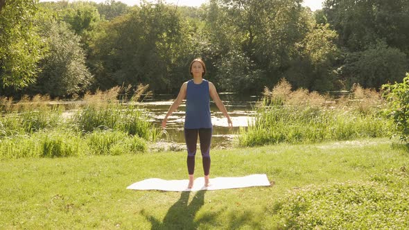 Stretching in park in the morning. Yoga exercises. Woman practicing yoga outdoors. alt