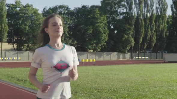 Athletic Young Girl Runs in the Stadium. Slow Motion alt