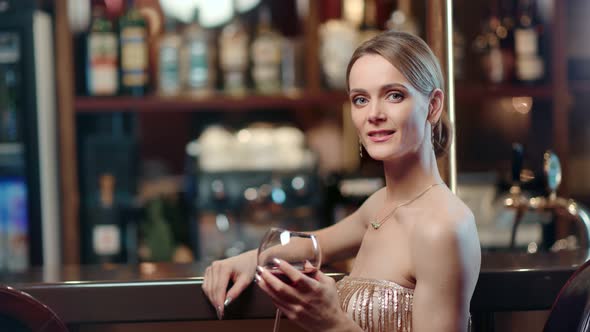 Beautiful Fashion Female Model Smiling Posing with Bocal of Wine at Bar alt