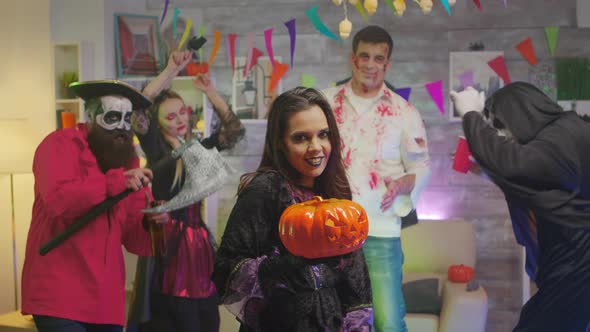 Beautiful Woman Dressed Up Like a Witch Doing Spells with a Pumpkin alt