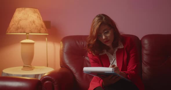 Doctor women marks the medicines on the notebook while she is sitting on the sofa at home alt